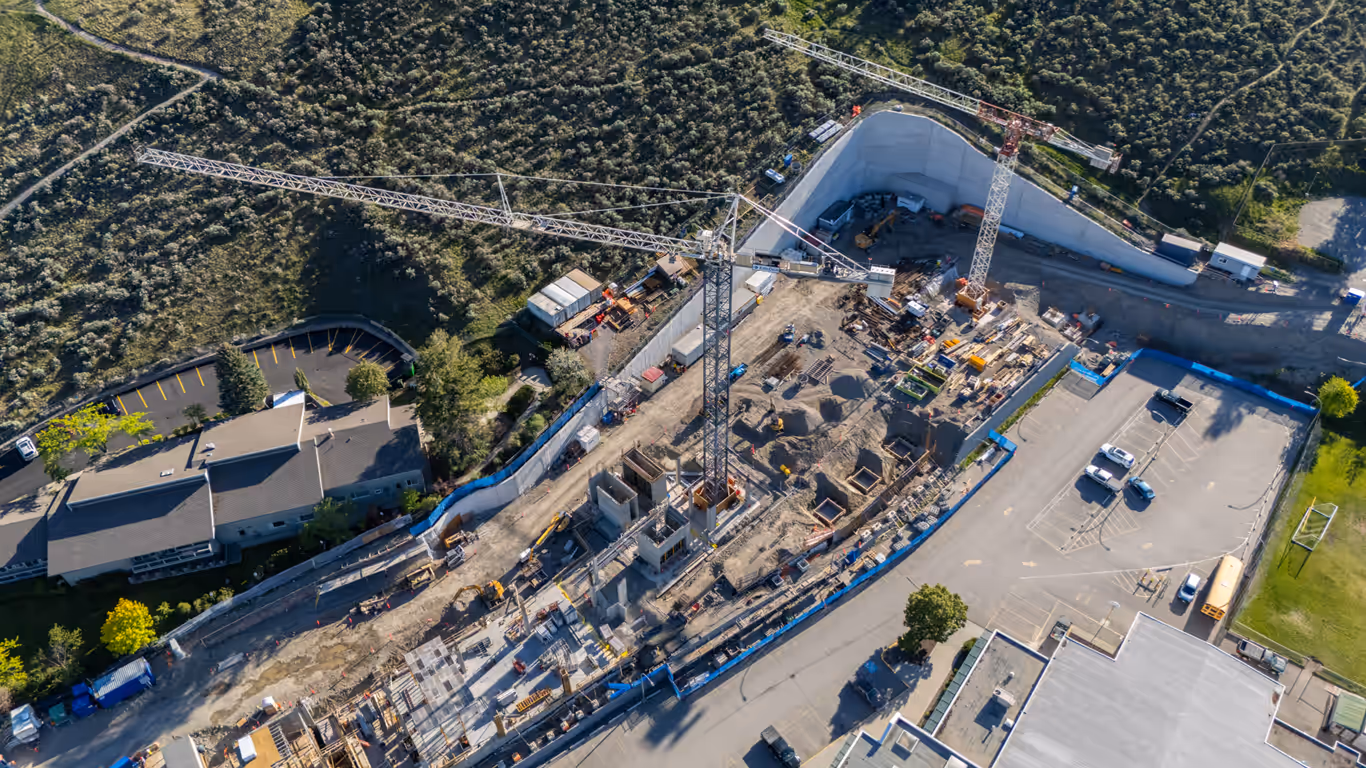 Aerial of the RS Foundation construction site for the Kamloops cancer centre with a tower crane and deep excavation, captured by Perseus Creative Studio.
