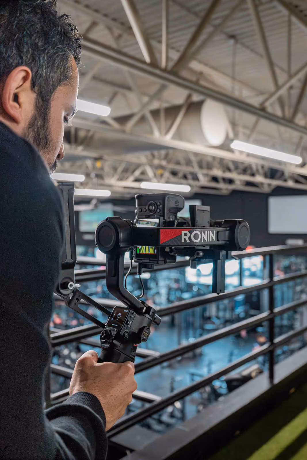 A Perseus videographer operates a DJI Ronin gimbal above a gym floor, capturing cinematic fitness content for a brand.