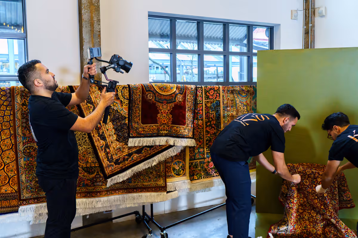 A Perseus videographer films a hand-knotted Persian rug in a showroom, capturing product detail for a retail client.
