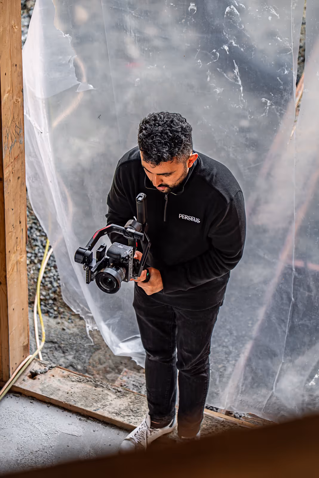 A Perseus videographer films on a construction site behind protective sheeting, documenting a real-estate development in progress.