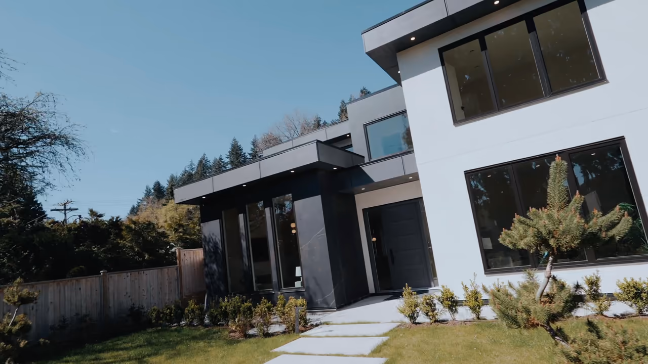 Modern two-storey home with a white-stucco upper, dark stone entry, and black-framed windows at Vela Homes’ 1384 Hope Rd build in North Vancouver, filmed by Perseus Creative Studio.