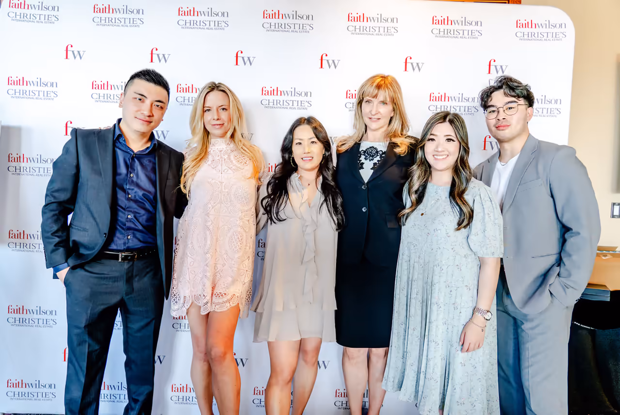 Faith Wilson Group team posing at a faithwilson | Christie’s International Real Estate step-and-repeat backdrop during the firm’s awards ceremony, photographed by Perseus Creative Studio.