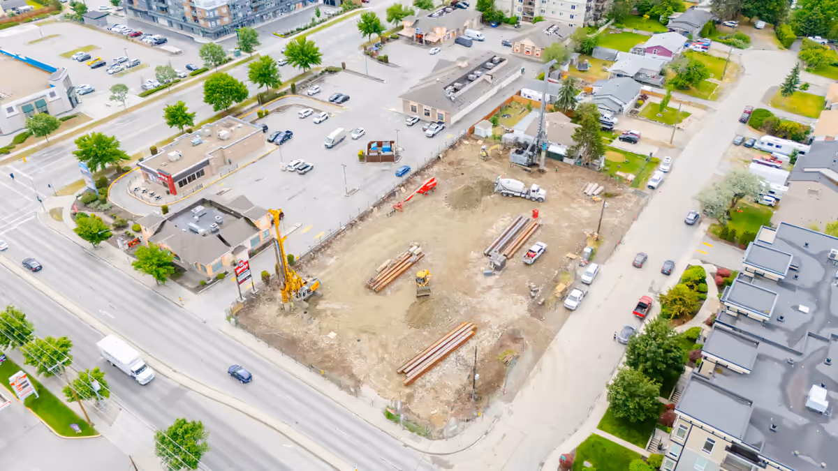 Excavator and stacked steel piling on the RS Foundation job site in Kelowna, documented by Perseus Creative Studio.