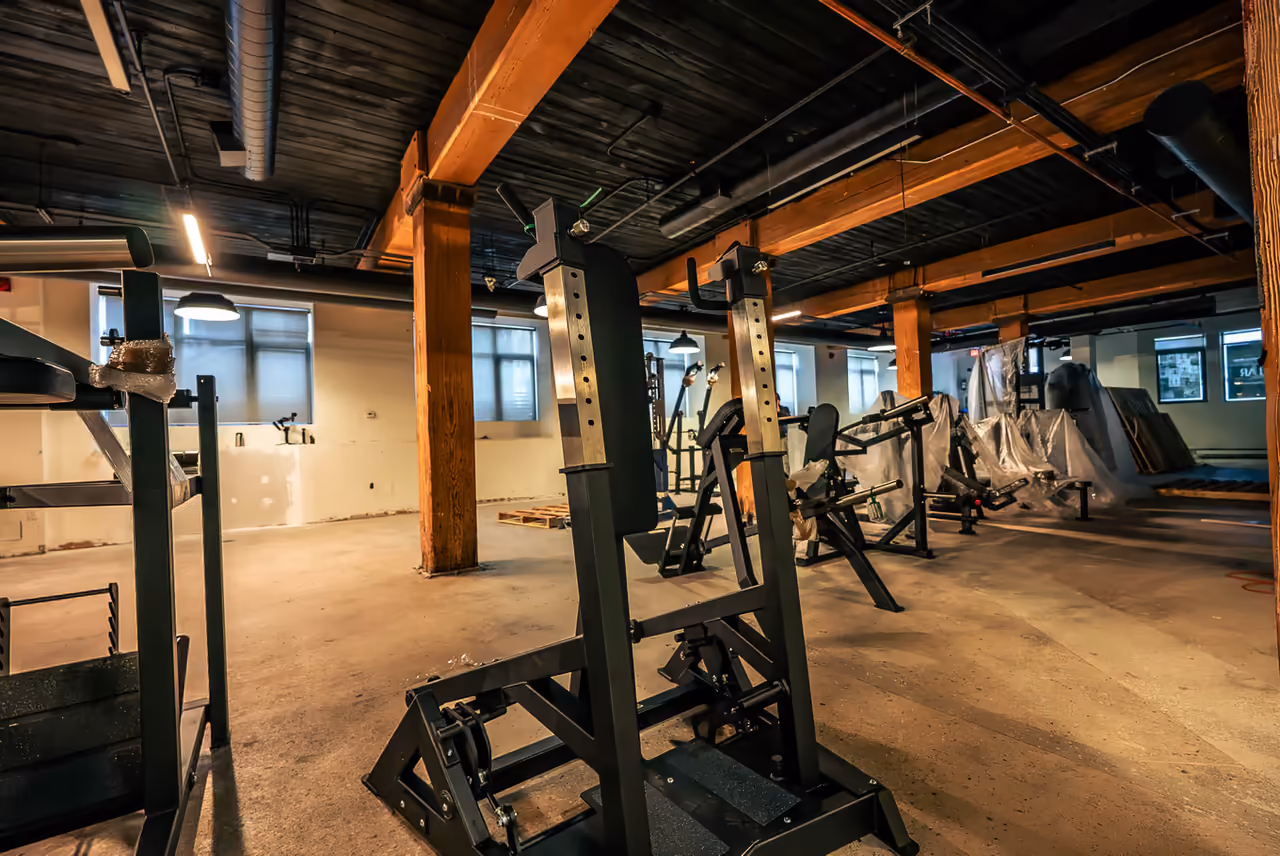 Squat racks and equipment being installed during the Toronto gym launch buildout, documented by Perseus Creative Studio.