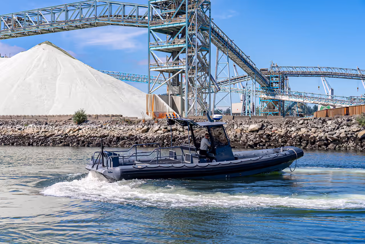 Ignition Marine’s USMI rigid-hull inflatable boat speeding past an industrial port, captured in a performance shoot by Perseus Creative Studio.
