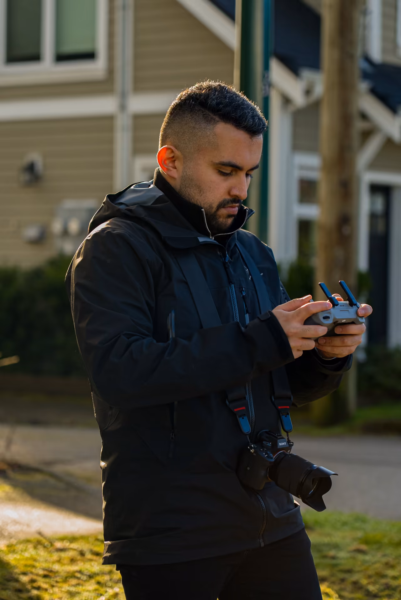 Perseus Creative Studio drone pilot flying an aerial camera with a handheld controller on a Vancouver residential street.